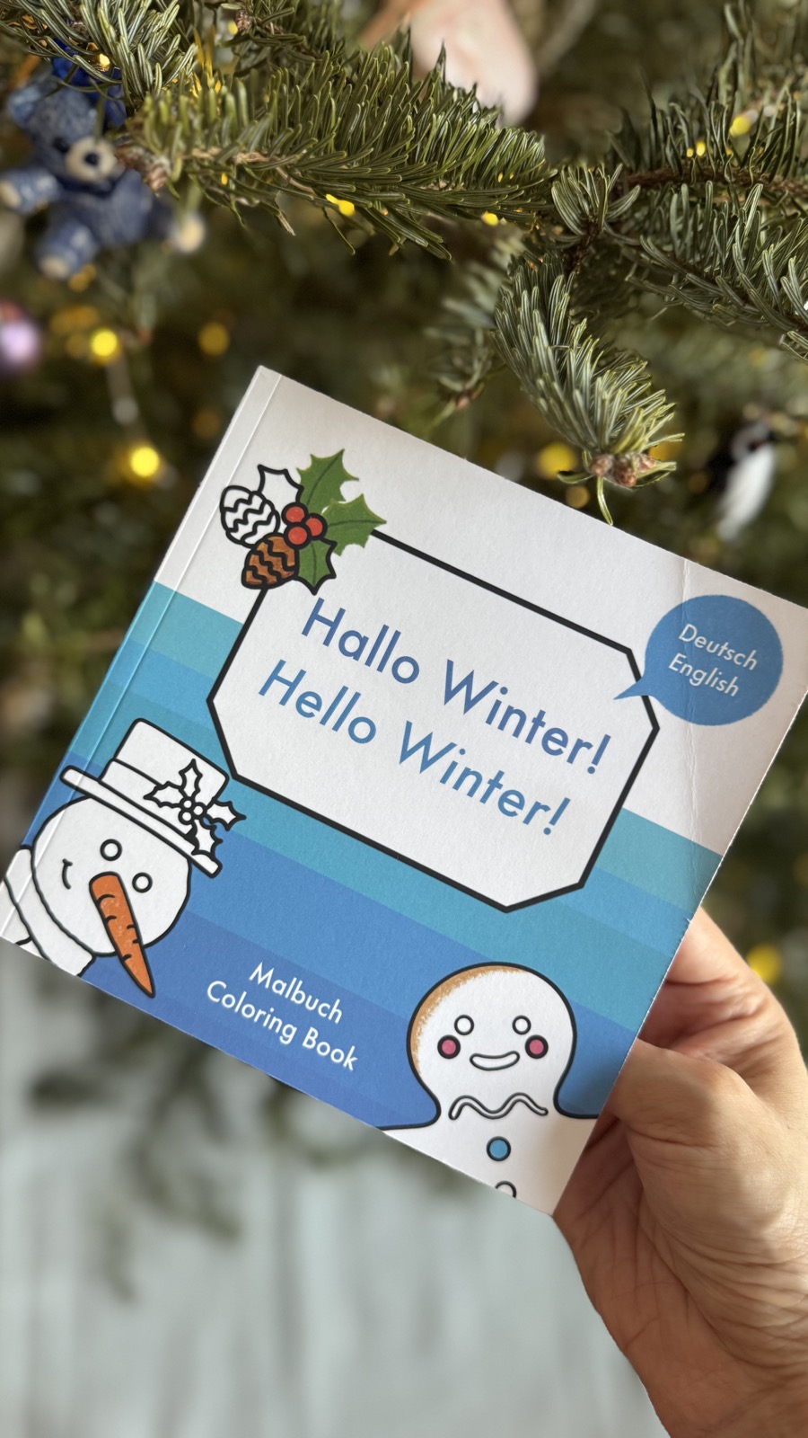 The Hallo Winter coloring book held in front of a tree